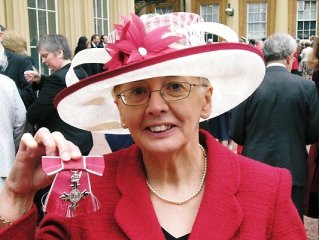 Cllr Mary Draycott holding up her MBE.