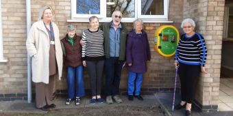 Council officers, tenants and Michael's family next to the defibrillator